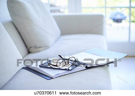 Stock Image - Eyeglasses and diary on living room sofa. Fotosearch