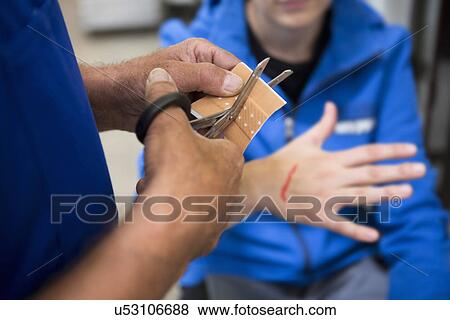 Factory worker applying first aid to colleague View Large Photo Image Stock Photo - Factory worker applying first aid to colleague. Fotosearch
