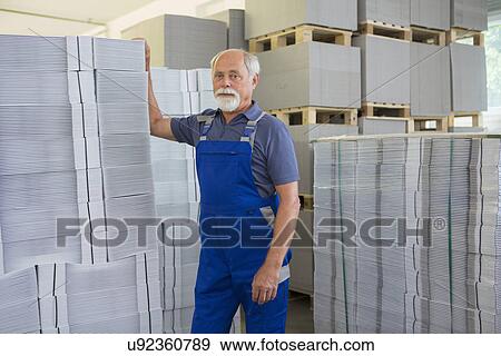 Stock Photo - Factory worker moving and stacking cardboard. Fotosearch