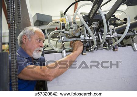 Stock Image - Factory worker working machinery. Fotosearch
