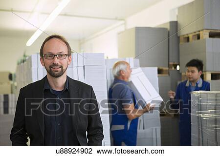 Stock Image - Factory workers moving and stacking cardboard. Fotosearch