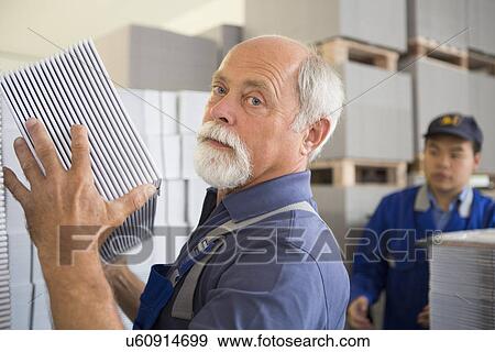 Stock Photo - Factory workers moving and stacking cardboard. Fotosearch