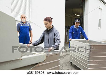 Factory workers moving containers of cardboard View Large Photo Image Stock Photo - Factory workers moving containers of cardboard. Fotosearch