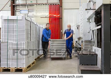 Stock Photo - Factory workers moving containers of cardboard. Fotosearch