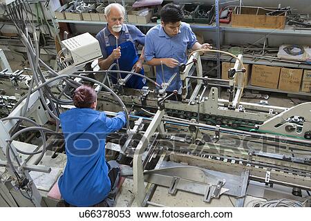Stock Image - Factory workers working machinery. Fotosearch