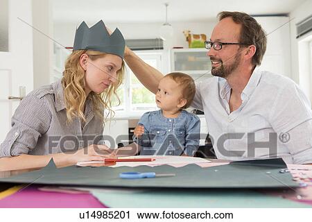 Stock Image - Family making paper crowns. Fotosearch