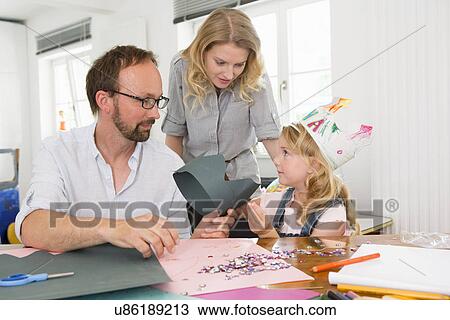 Stock Image - Family making paper crowns. Fotosearch