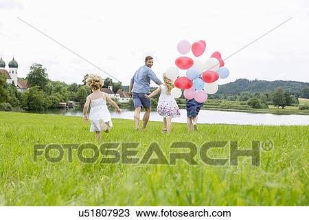 Family running through field with balloons View Large Photo Image Stock Image - Family running through field with balloons. Fotosearch