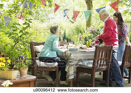 Stock Image - Family sitting down for an outdoor meal. Fotosearch