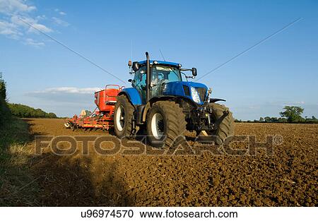 Farmer driving tractor and drilling seed corn in ploughed field View Large Photo Image Stock Image - Farmer driving tractor and drilling seed corn in ploughed field. Fotosearch