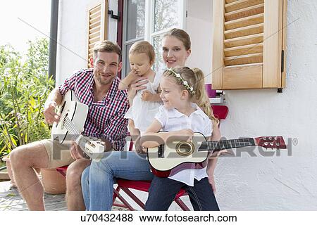 Stock Photo - Father playing guitar with family. Fotosearch