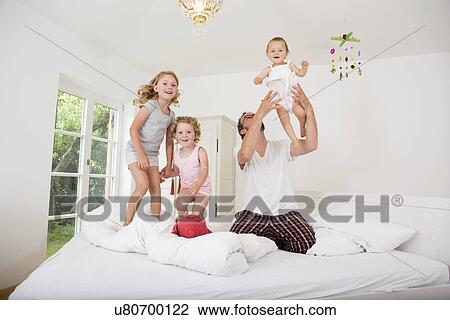 Father playing with daughters on bed View Large Photo Image Stock Image - Father playing with daughters on bed. Fotosearch