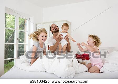 Father playing with daughters on bed View Large Photo Image Stock Photography - Father playing with daughters on bed. Fotosearch