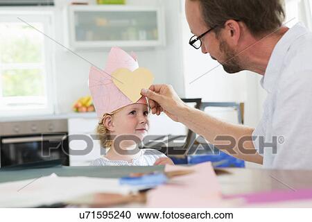 Father putting heart shape on daughter's paper crown View Large Photo Image Stock Image - Father putting heart shape on daughter's paper crown. Fotosearch