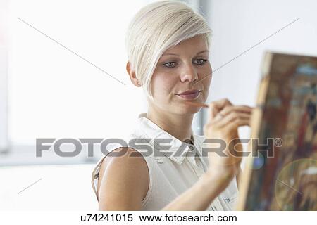 Stock Photography - Female artist painting at easel. Fotosearch