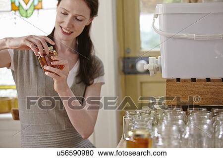Female beekeeper in kitchen, bottling filtered honey from beehive View Large Photo Image Stock Image - Female beekeeper in kitchen, bottling filtered honey from beehive. Fotosearch