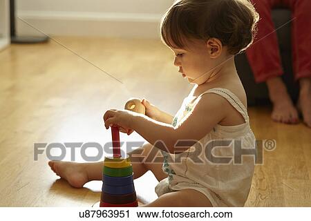 Female toddler sitting on living room floor playing with toy building rings View Large Photo Image Stock Image - Female toddler sitting on living room floor playing with toy building rings. Fotosearch
