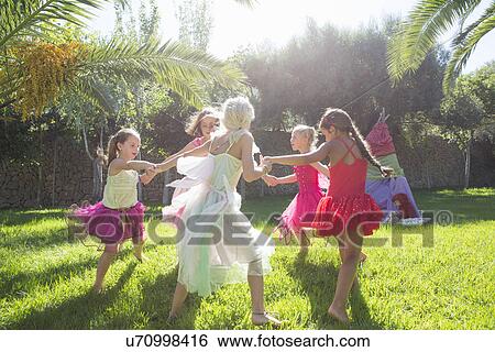 Stock Photograph - Five energetic girls in fairy costume playing in garden. Fotosearch