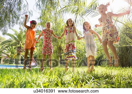 Stock Image - Five girls energetic girls jumping in garden. Fotosearch