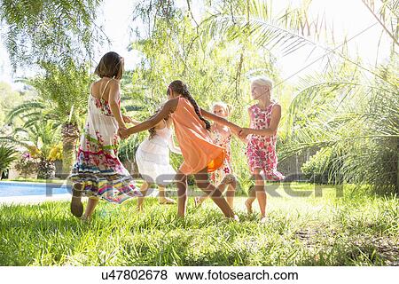 Stock Photo - Five girls playing ring a ring a roses in garden. Fotosearch