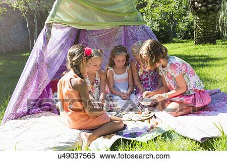 Stock Photography - Five girls playing with toy tea set in front of teepee. Fotosearch