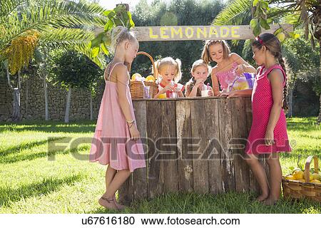 Stock Image - Five girls pouring lemonade and chatting at lemonade stand in park. Fotosearch