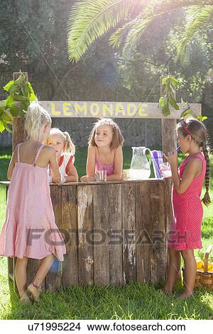 Picture - Four girls buying and selling at lemonade stand in park. Fotosearch