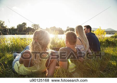 Stock Photo - Four young adult friends reclining on riverbank. Fotosearch