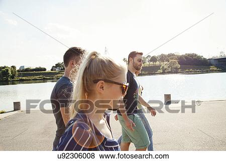 Stock Photo - Four young friends walking along riverside. Fotosearch