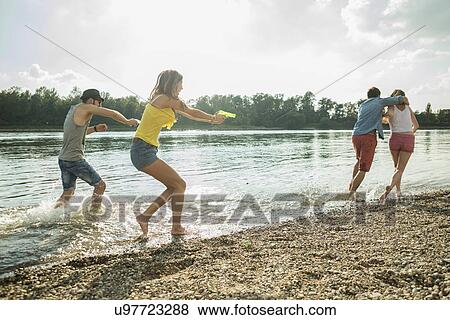 Stock Photo - Friends playing with water pistols in lake. Fotosearch