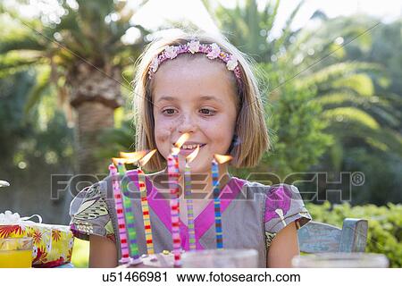Girl at birthday party looking at cake with candles View Large Photo Image Stock Image - Girl at birthday party looking at cake with candles. Fotosearch