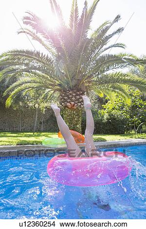 Girl diving into inflatable ring in garden swimming pool View Large Photo Image Picture - Girl diving into inflatable ring in garden swimming pool. Fotosearch