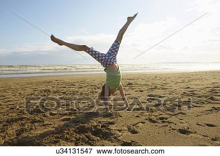 Stock Photo - Girl doing handstand on beach, Camber Sands, Kent, UK. Fotosearch