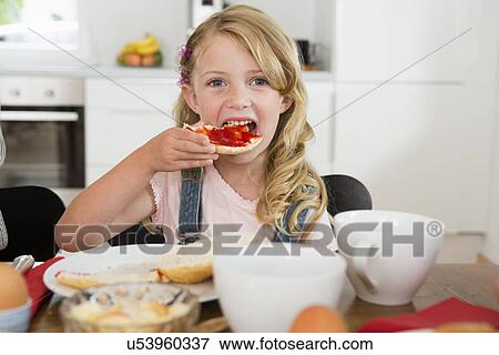 Girl eating at kitchen table View Large Photo Image Stock Photo - Girl eating at kitchen table. Fotosearch