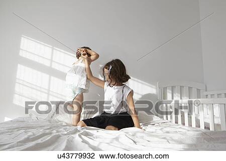 Girl giving helping hand to female toddler cousin to toddle on bed View Large Photo Image Stock Image - Girl giving helping hand to female toddler cousin to toddle on bed. Fotosearch