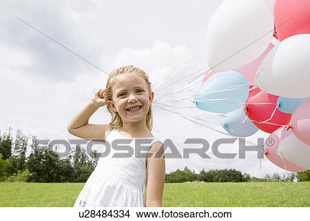 Picture - Girl holding a bunch of balloons. Fotosearch