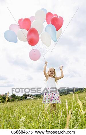 Girl holding balloons in field View Large Photo Image Stock Photography - Girl holding balloons in field. Fotosearch