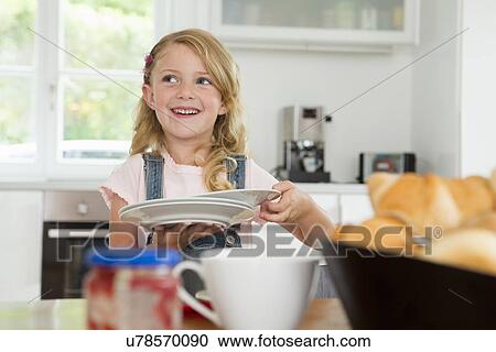 Girl holding plates and setting kitchen table View Large Photo Image Stock Image - Girl holding plates and setting kitchen table. Fotosearch