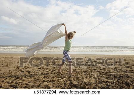 Girl holding up blanket on breezy beach, Camber Sands, Kent, UK View Large Photo Image Picture - Girl holding up blanket on breezy beach, Camber Sands, Kent, UK. Fotosearch