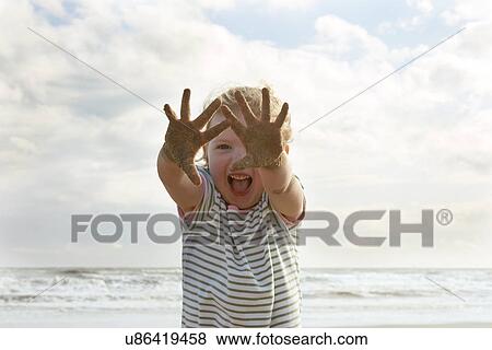 Girl holding up sandy hands on beach, Camber Sands, Kent, UK View Large Photo Image Stock Photo - Girl holding up sandy hands on beach, Camber Sands, Kent, UK. Fotosearch