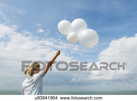 Girl holding white balloons outdoors View Large Photo Image Picture - Girl holding white balloons outdoors. Fotosearch