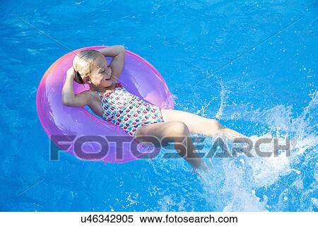 Girl lying back on inflatable ring in garden swimming pool View Large Photo Image Stock Photography - Girl lying back on inflatable ring in garden swimming pool. Fotosearch
