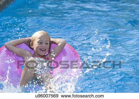 Girl lying on her back on inflatable ring in garden swimming pool View Large Photo Image Stock Photo - Girl lying on her back on inflatable ring in garden swimming pool. Fotosearch