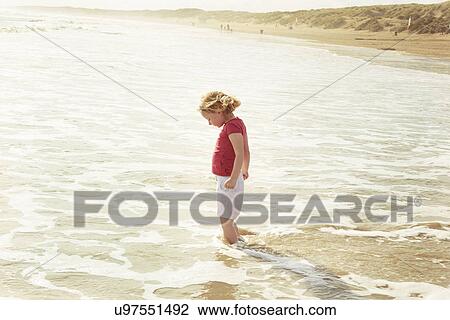 Stock Image - Girl paddling in sea, Camber Sands, Kent, UK. Fotosearch