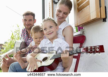Girl playing guitar with family View Large Photo Image Stock Photo - Girl playing guitar with family. Fotosearch