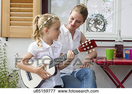 Stock Photo - Girl playing guitar with mother. Fotosearch