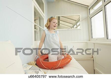 Girl playing with life belt on holiday apartment seat View Large Photo Image Stock Photo - Girl playing with life belt on holiday apartment seat. Fotosearch