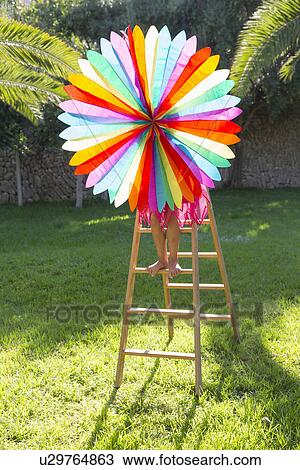 Stock Image - Girl putting up decoration in garden. Fotosearch