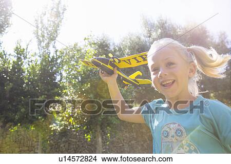 Girl running with toy airplane in garden View Large Photo Image Picture - Girl running with toy airplane in garden. Fotosearch