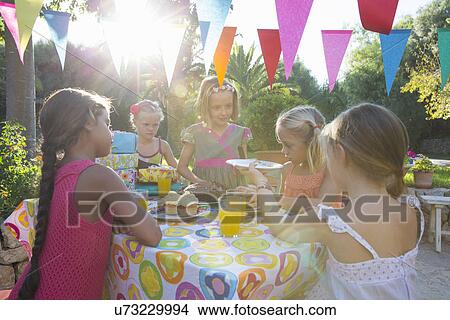 Picture - Girl serving friends birthday cake. Fotosearch